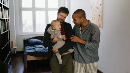 Ouders met hun kind. Twee vaders in een kamer, de linker vader houdt een baby vast.