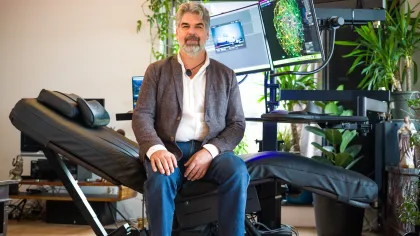 Portret van Bjorn. Hij zit op zijn speciale in hoogte verstelbare ligstoel. Aan de voorkant van de ligstoel zijn er 2 computerschermen verbonden om te kunnen werken. 