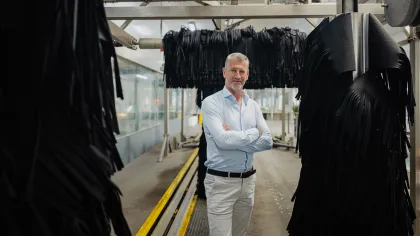 Martin Kniest staat in een wasstraat tussen de grote zwarte wasdraaiers. Zijn armen houdt hij gekruisd voor zn borst.