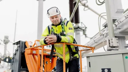 Portet van Siemen. Hij staat op een oranje installatiemachine op het werk en heeft veiligheidskleding aan en een helm.