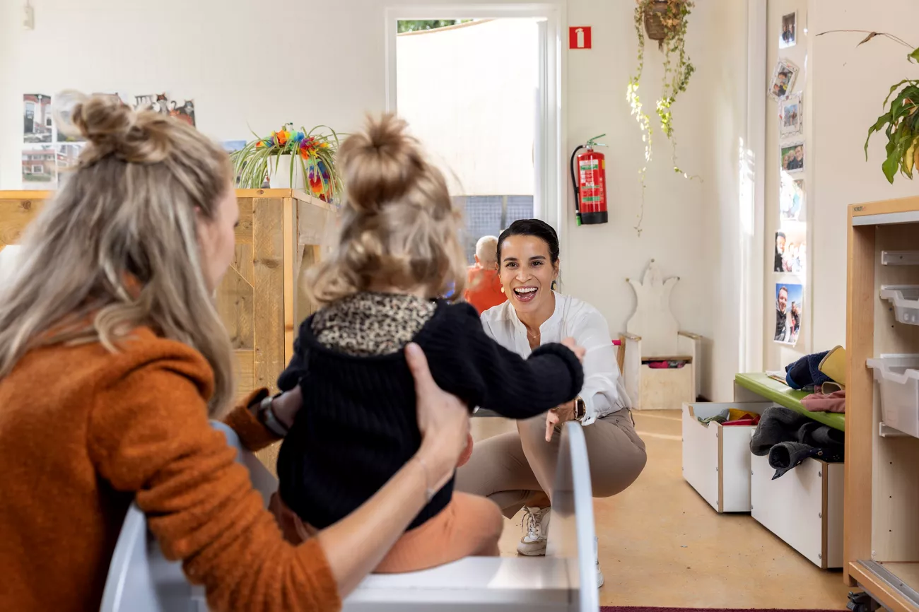 Foto van Lisette aan het werk en moeder die haar kind ophaalt. Lisette volgde gratis de opleiding pedagogisch medewerker en werkt nu bij de kinderopvang