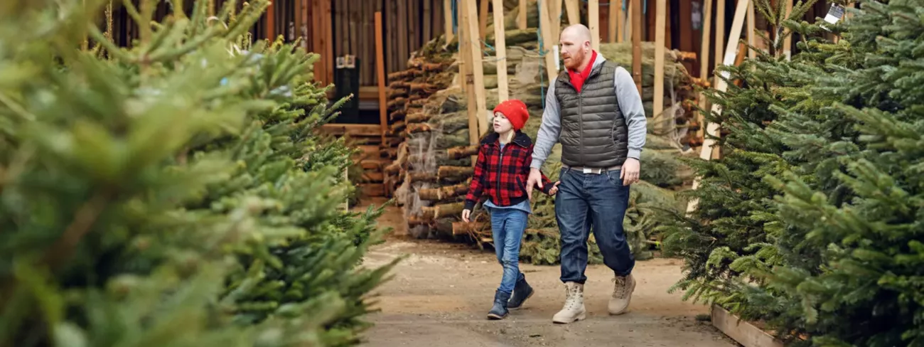 Man die kerstboom koopt met zijn kind