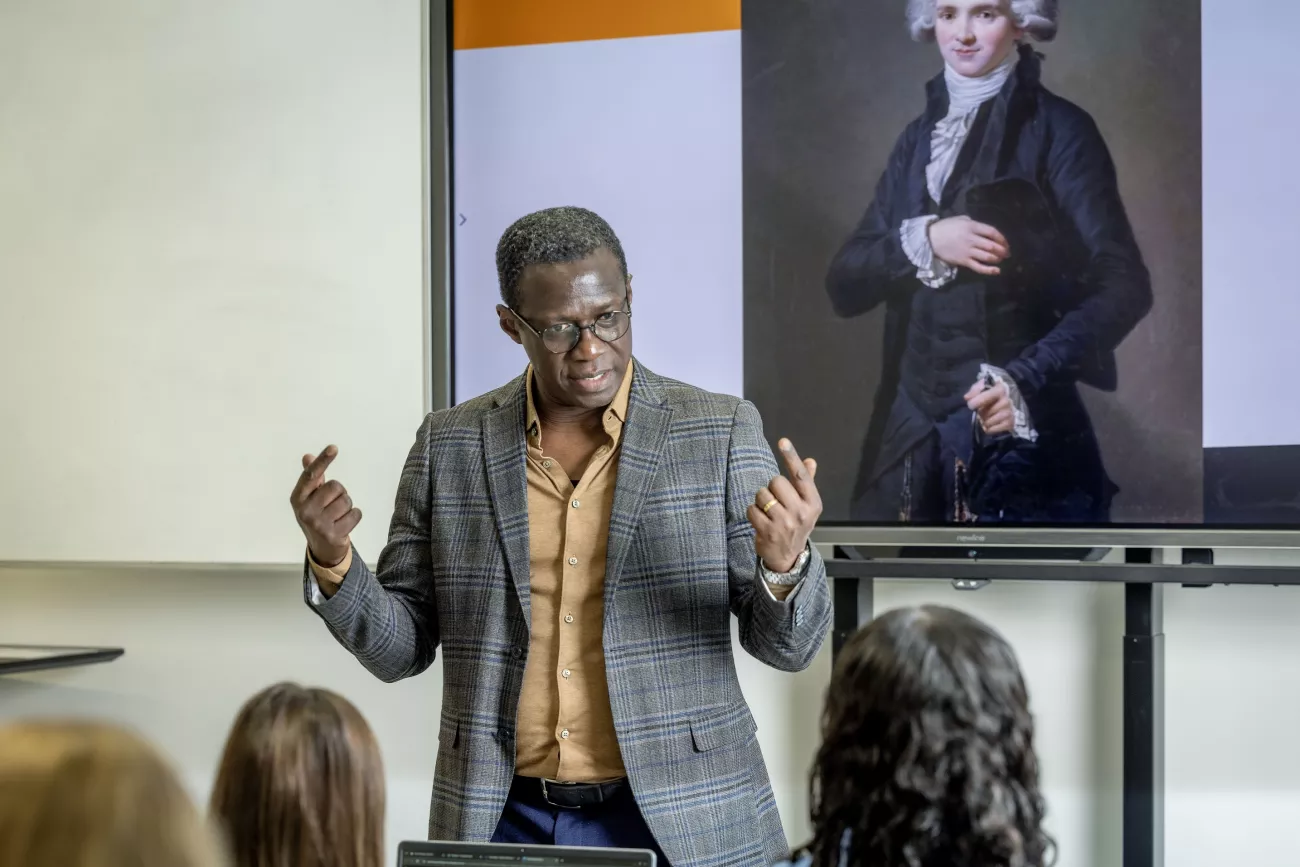 Mamadou Seck, docent bij het Coenecoop College, staat voor een klas