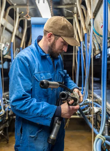 Foto van boer Arjen aan het werk bij de melkmachine