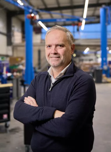 Portret van Johan Bogert directeur van PreWorxs. Hij staat in een hal met zijn armen gekruist en kijkt in de camera.