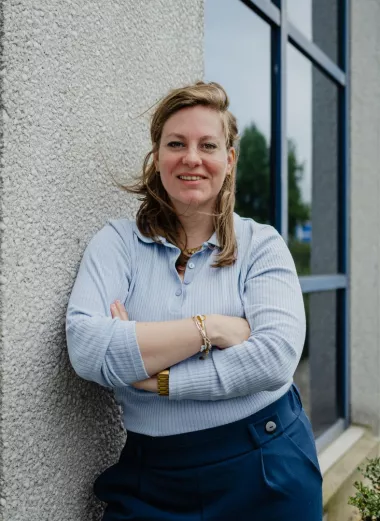 Imke Paulussen, werkgeversadviseur, leunt buiten tegen een muur van een kantoor