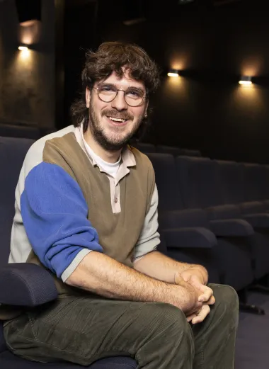 Portret van Frank. Hij zit in een bioscoopzaal op zijn werk.