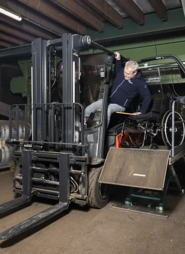 Portret van Ronald. Hij zit in de schaarlift en stapt in zijn heftruck. 