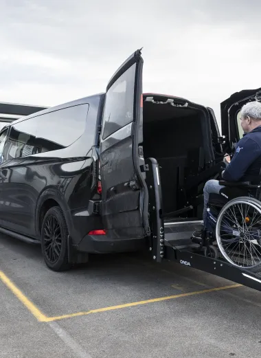 Portret van Ronald. Hij gaat zijn aangepast bus in met de autolift.