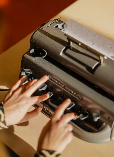 Kim typt op haar brailleprinter. 