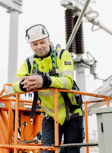Portet van Siemen. Hij staat op een oranje installatiemachine op het werk en heeft veiligheidskleding aan en een helm.
