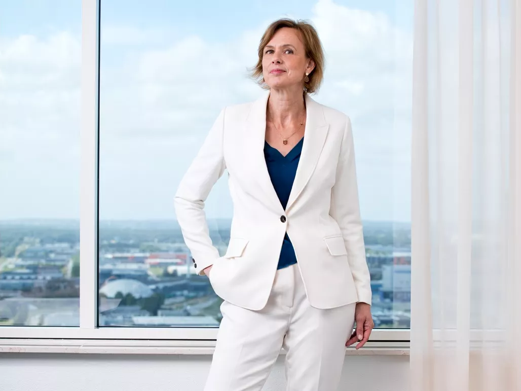 Ellen Jacobs, landelijk manager voorzieningen bij UWV, staat voor een raam in een wit pak