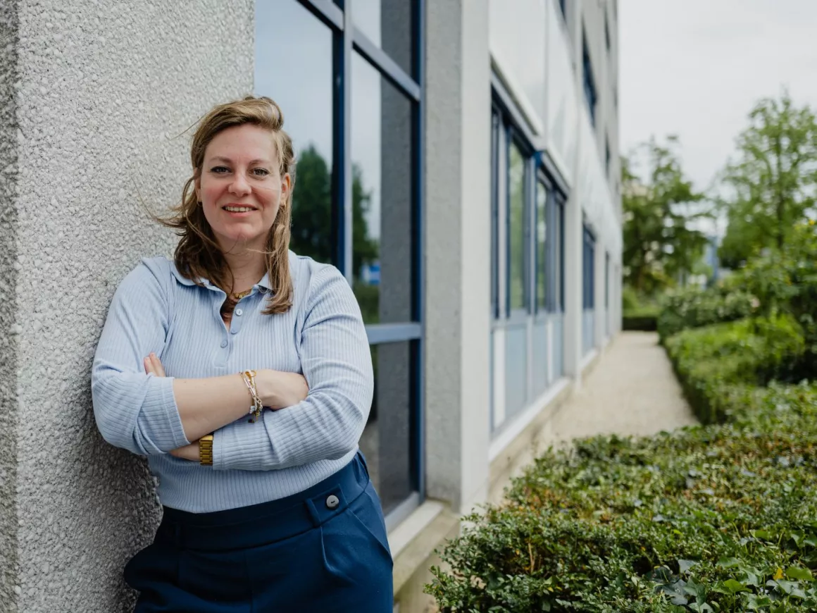 Imke Paulussen, werkgeversadviseur, leunt buiten tegen een muur van een kantoor