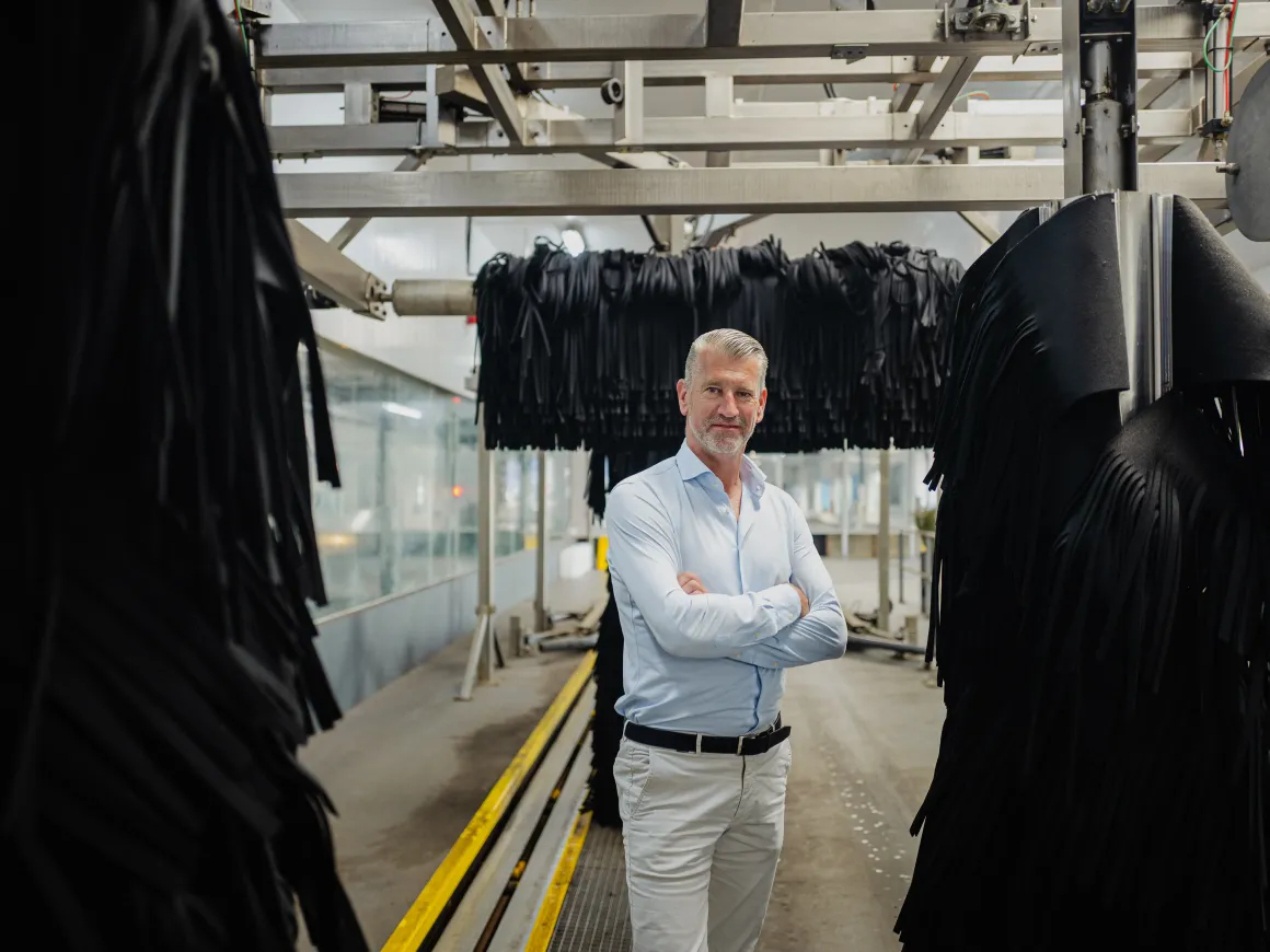 Martin Kniest staat in een wasstraat tussen de grote zwarte wasdraaiers. Zijn armen houdt hij gekruisd voor zn borst.